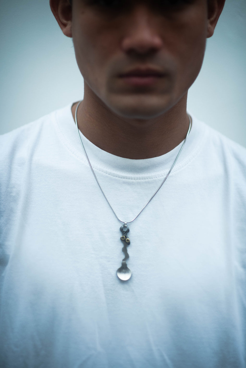 Model wearing the Wiggle Spoon Pamor Necklace by Lievik Atelier, handcrafted with Pamor Wos Wutah (Damascus steel) and adjustable 1.2 mm paracord.