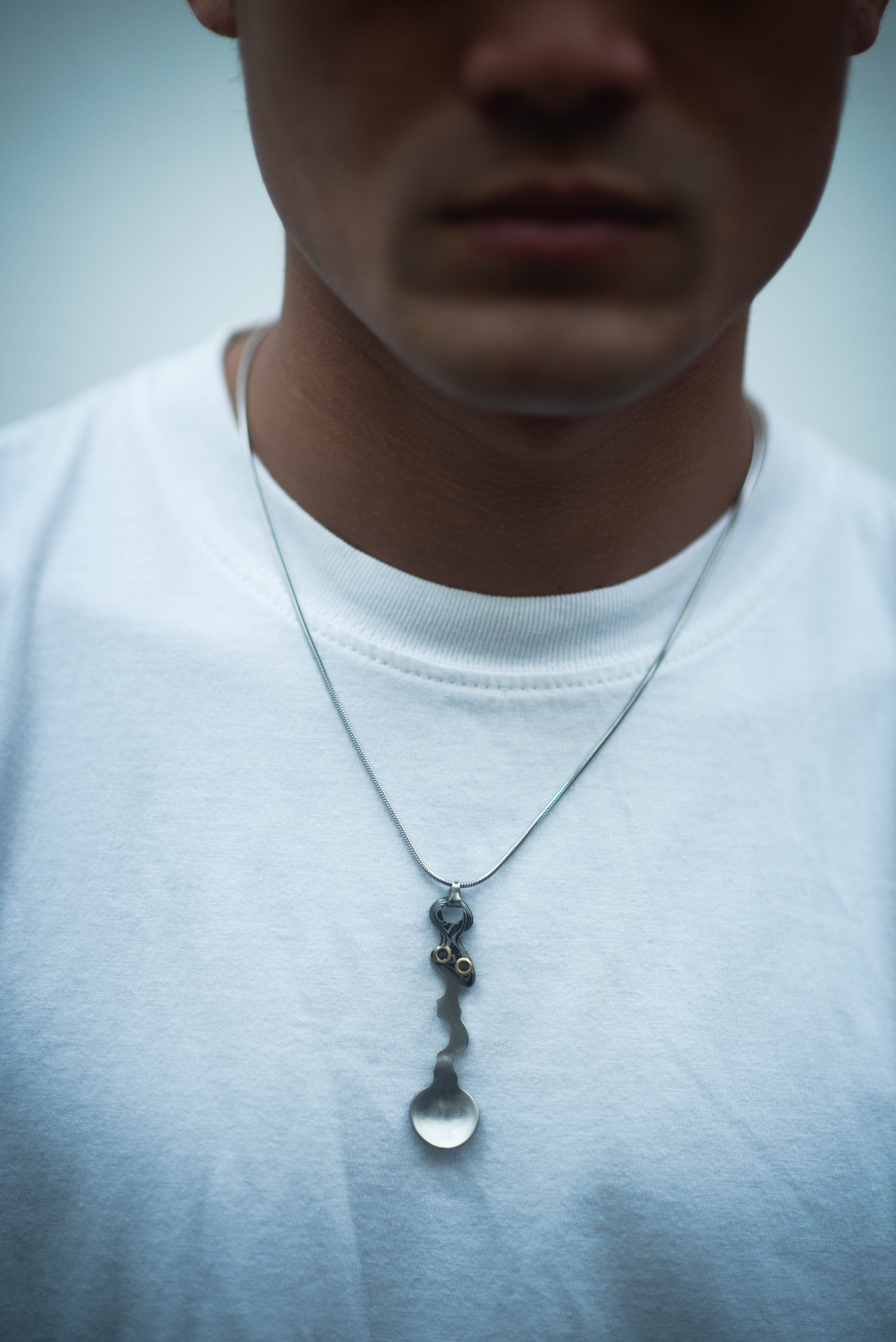 Model wearing the Wiggle Spoon Pamor Necklace by Lievik Atelier, handcrafted with Pamor Wos Wutah (Damascus steel) and adjustable 1.2 mm paracord.