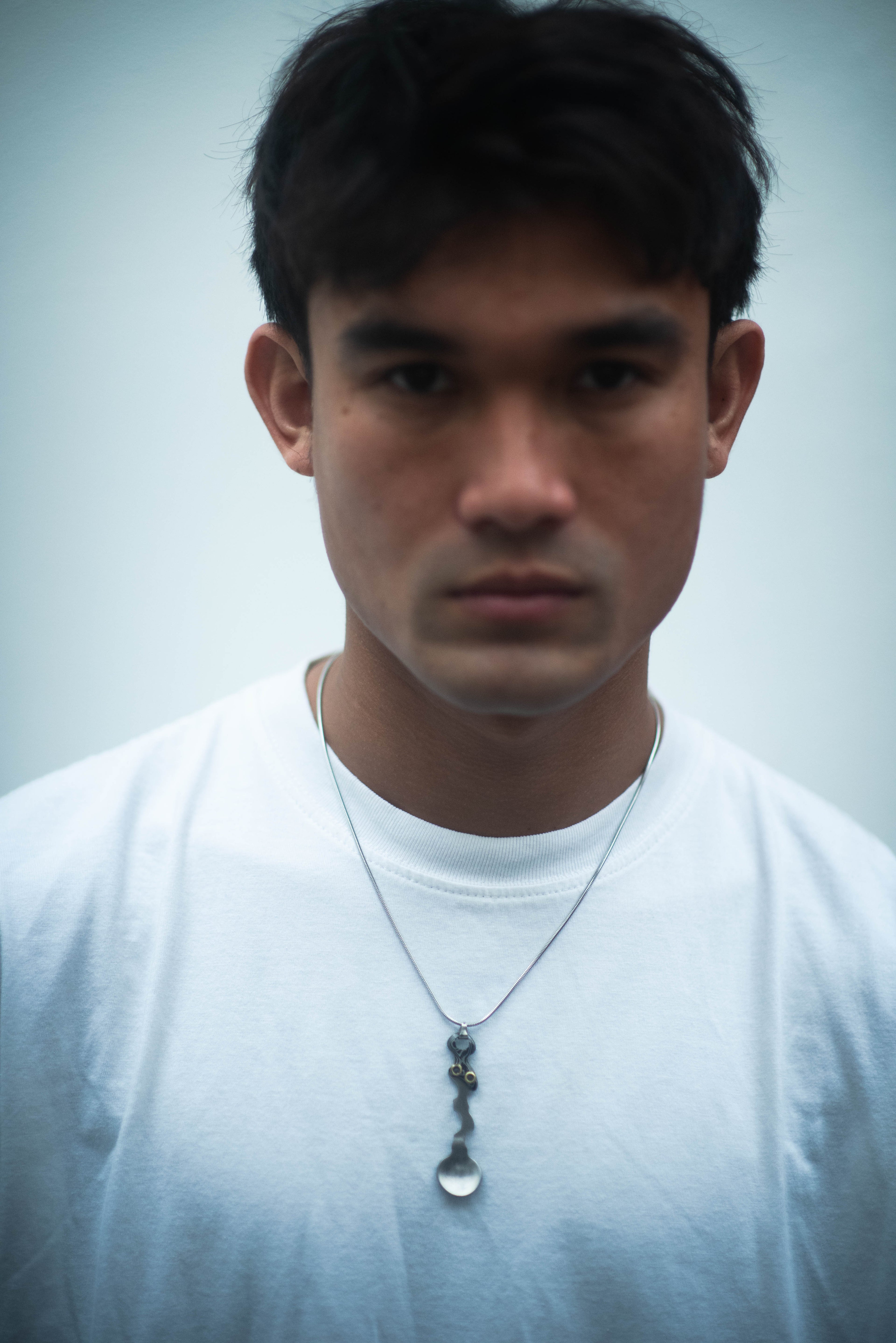 Model wearing the Wiggle Spoon Pamor Necklace by Lievik Atelier, handcrafted with Pamor Wos Wutah (Damascus steel) and adjustable 1.2 mm paracord.